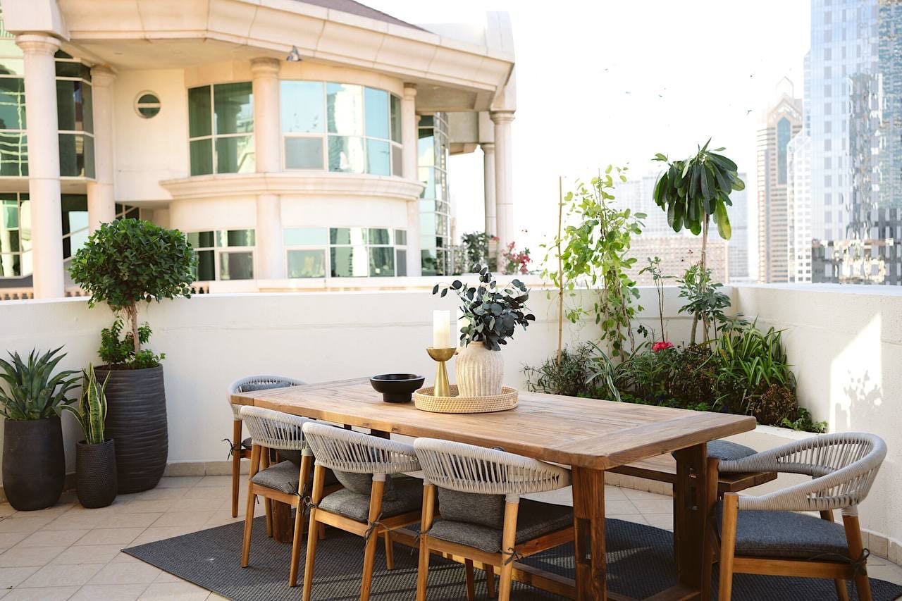 Sunlit terrace dining space with natural wood and greenery at Al Murooj